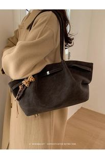 Detail of retro suede tote bag with leopard bow accent styled on a beige trench coat