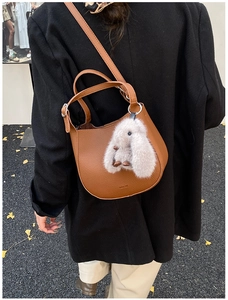 Brown litchi leather bucket bag with cute plush rabbit charm shown on a female model