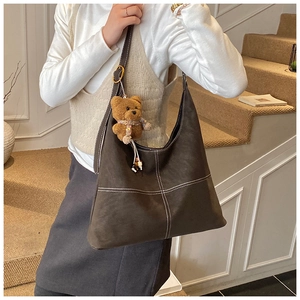 Detail of vintage brown tote bag with contrast stitching and teddy bear charm