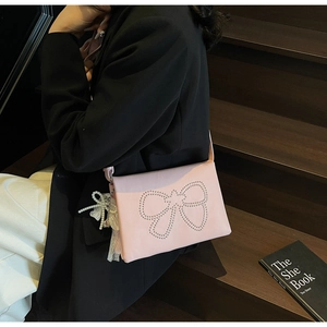Detail of pink crossbody bag featuring silver rivet bow and elegant pearl lace charm