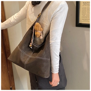 Detail showing deep brown textured faux leather tote bag with white contrast stitching