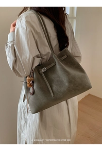 Detail view of retro olive gray tote bag featuring fine straps and a leopard bear charm