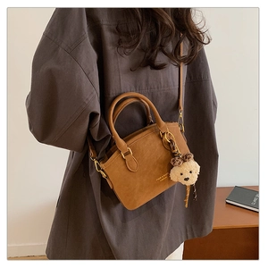 Close-up of vintage brown crossbody bag with matte texture and cute bear pendant