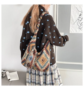 Detailansicht des bunten geometrischen Strickmusters und Metall-Logos auf der Plüschtasche