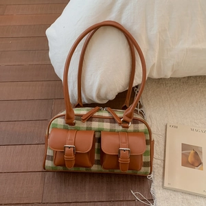 Close-up of vintage plaid handbag with green texture and brown leather pockets
