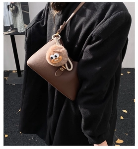 Sac à bandoulière marron en cuir grainé avec charm en peluche sur un mannequin