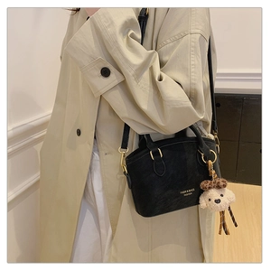 Detail view of black faux leather bag with gold hardware and plush puppy charm