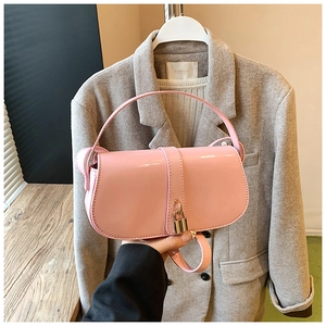 Detailed macro view of pink patent leather handbag with golden lock and top handle
