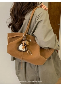 Detail of tan leather tote bag with heart mirror and leopard print tassel accessory