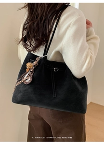 Detail of a black matte tote bag with silver metal buckles and leopard print pendant