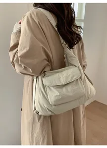 Model wearing a lightweight beige nylon tote bag with front pocket and wide strap