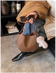 Detail of brown lychee grain leather bucket bag with cute white plush rabbit charm
