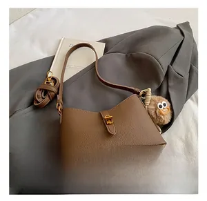 Gros plan détaillé du sac à main en cuir marron avec fermoir doré et charme en peluche