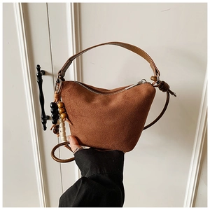 Detalle de bolso bucket marrón de ante con borla de cuentas de madera y cremallera metálica