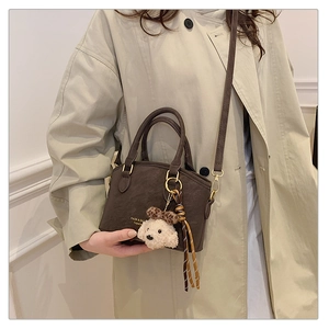 Brown faux leather crossbody bag detail with cute plush charm and brand logo print