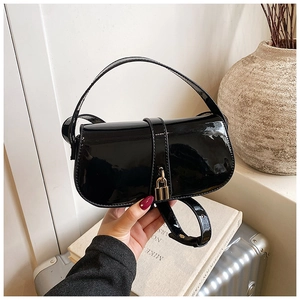Close-up of a glossy black patent leather handbag featuring a stylish gold padlock detail