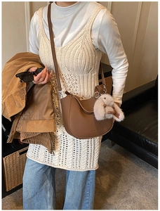 Close-up of brown litchi grain leather bucket bag with a cute plush bunny pendant