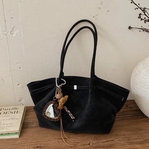 Detail of black suede tote bag with silver trim and leopard print mirror charm