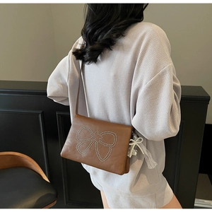 Detailed back view of brown square crossbody bag with rivet bow and lace charm