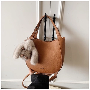 Detail of brown litchi pattern leather bucket bag with a plush rabbit charm