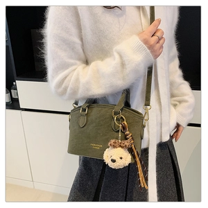 Detail of olive green vintage handbag with teddy bear charm and braided tassel