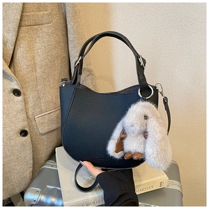 Detail view of black pebble leather hobo bag with cute grey plush bunny pendant charm