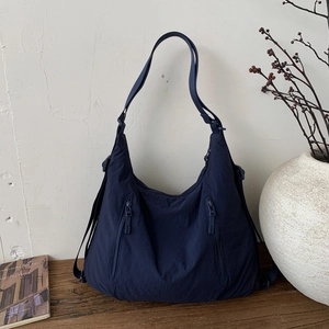 Détail du sac cabas en nylon bleu marine avec double fermeture éclair sur surface en bois