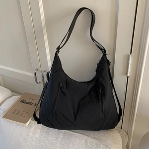 Détail d'un sac fourre-tout noir en nylon avec fermetures éclair sur canapé