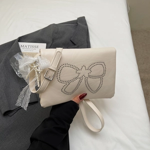 Detail of off-white leather handbag with metal rivet bow design and pearl lace charm