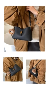 Détail d'un sac noir en cuir grainé avec boucle dorée et breloque en peluche douce