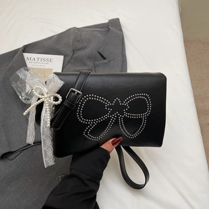 Detail of black square crossbody bag featuring silver stud bow and lace pearl charm