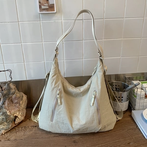 Détail d'un sac cabas en nylon beige avec texture plissée et poches zippées verticales