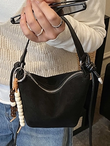 Bolso bucket negro minimalista con colgante de cuentas y cremallera plateada