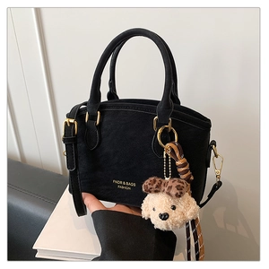 Detail of black matte suede handbag with gold logo and leopard bow teddy bear charm