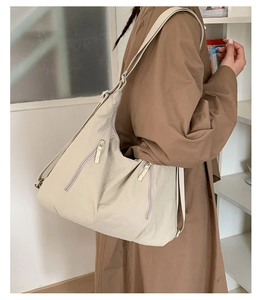 Vue latérale d'un sac fourre-tout crème multi-poches porté avec un trench-coat décontracté