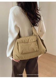 Detail of a khaki nylon tote bag showing the large front flap pocket and adjustable strap