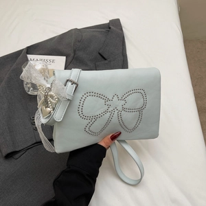 Detail of light blue crossbody bag with silver rivets bow and pearl lace charms