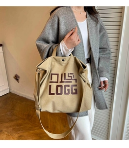 Detail of khaki canvas tote bag with brown LOGG print and dual handle straps