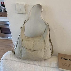 Close-up of beige nylon tote bag with functional front pocket and adjustable strap
