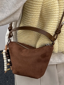 Bolso cubo de ante marrón en forma de media luna con bandolera y colgante de cuentas
