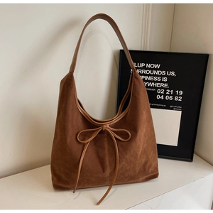 Close-up of brown suede hobo bag featuring a delicate bow tie detail and soft texture