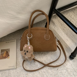 Dettaglio borsa bowling vintage in pelle marrone con ciondolo a forma di cucciolo morbido