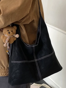 French vintage black suede tote bag with white contrast stitching and bear charm on model