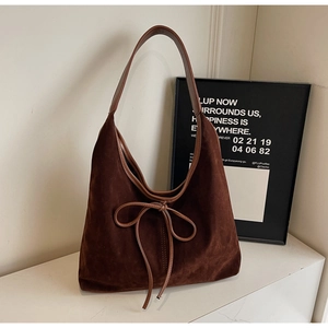 Detail of chocolate suede hobo bag with delicate bow knot and smooth leather strap