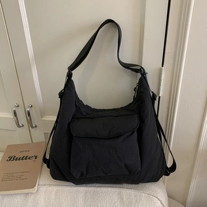 Close-up of black canvas tote bag with large front flap pocket and adjustable strap