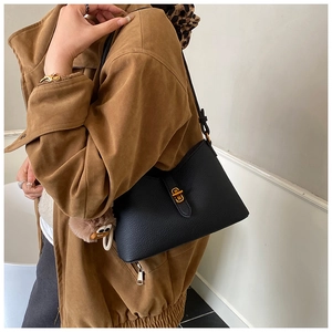 Détail du sac à main noir en cuir grainé avec fermoir doré et breloque en peluche