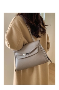 Detail of taupe leather tote bag showing textured grain and silver buckle on shoulder