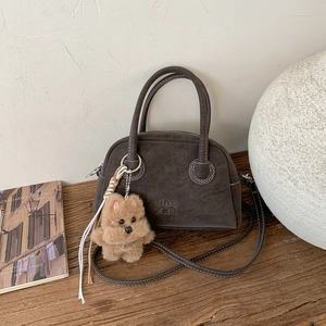 Dettaglio borsa bowling in camoscio grigio scuro con logo impresso e ciondolo a cane