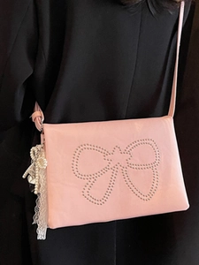 Pink leather crossbody square bag with rivet bow design and pearl charms on black blazer