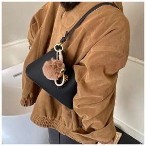 Détail d'un sac bandoulière en cuir grainé noir avec un charmant canard en peluche brun